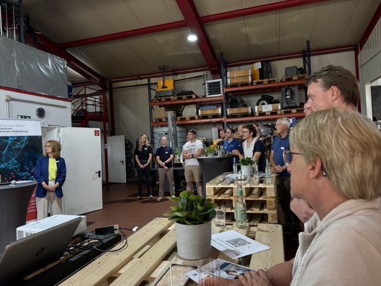 Teilnehmende einer Mittelstand-Digital-Präsentation in einer Werkhalle