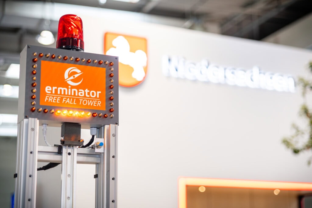 Erminator Free Fall Tower with red warning light on the aluminum frame in front of the trade fair stand of the State of Lower Saxony.