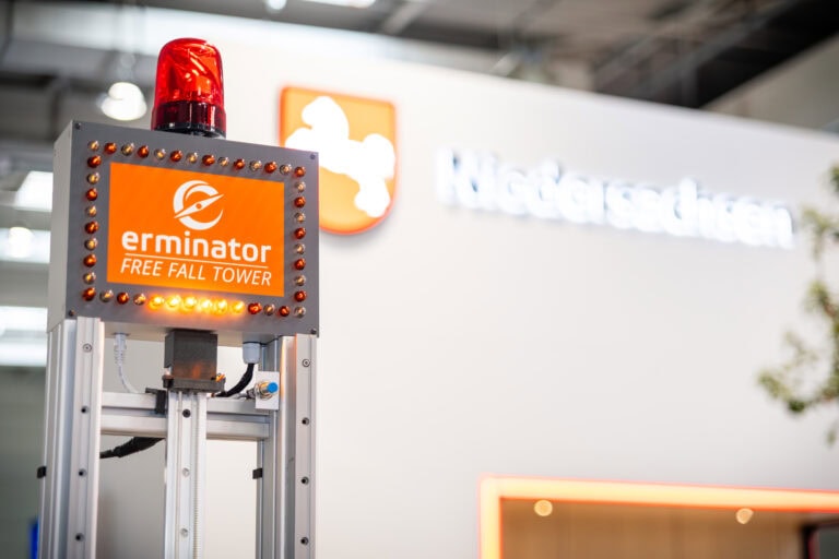 Erminator Free Fall Tower with red warning light on the aluminum frame in front of the trade fair stand of the State of Lower Saxony.